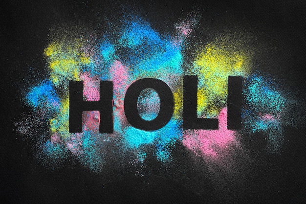 Word HOLI written on colorful powders against dark background