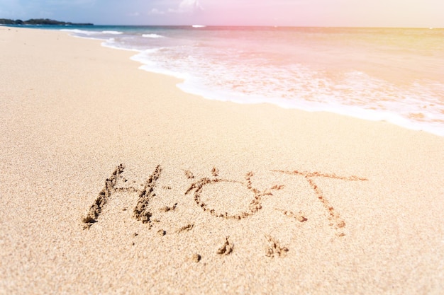 The word HOT written in the sand on beach