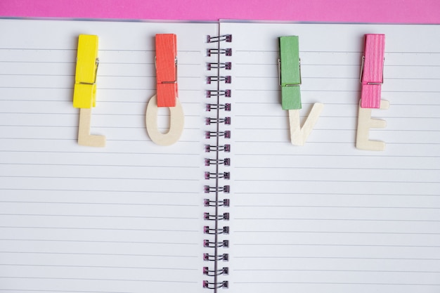 word LOVE in blank book on pink background with space for text