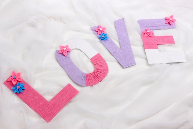 Word Love created with brightly colored knitting yard on fabric background