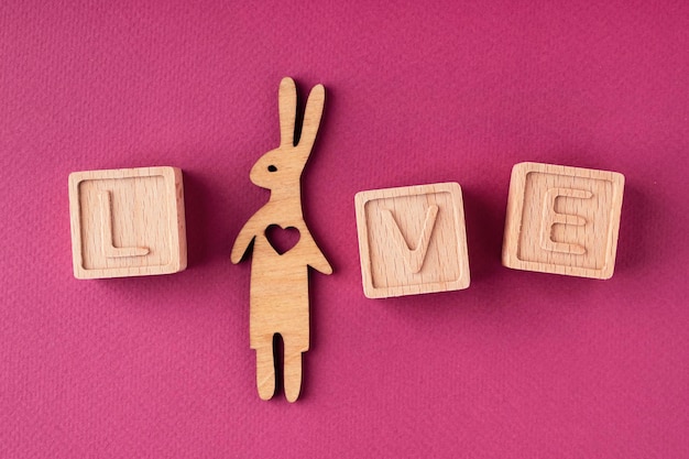 The word love is made up of wooden cubes on a bright pink background flat flat, top view. Love Message. The concept of a greeting card for Valentine's Day, Mother's Day, Women's Day, March 8