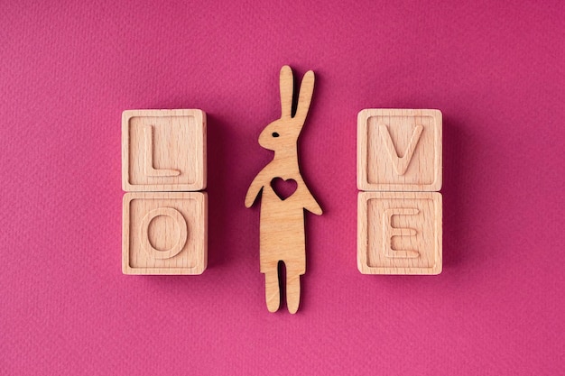 The word love is made up of wooden cubes on a bright pink background flat lay top view The theme of love and romance The concept of a greeting card for Valentine's Day Mother's Day Women's Day