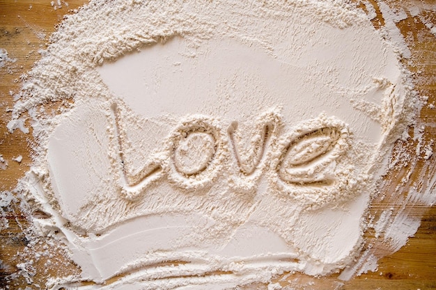 The word LOVE is written in flour on a wood texture Copy space Conceptual