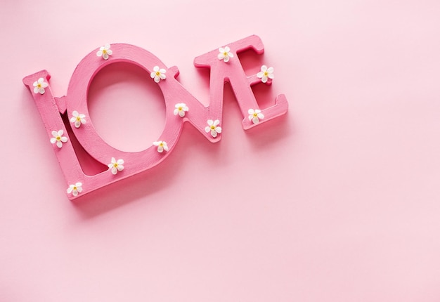 Word love and white spring flowers on a pink background and copy space for text. Creative concept inscription love