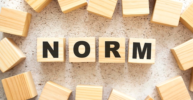 The word NORM consists of wooden cubes with letters top view on a light background Work space