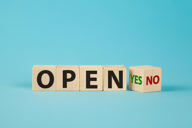 The word OPEN is written on wooden cubes The hand turns the wooden cube and changes the word NO OPEN to YES OPEN