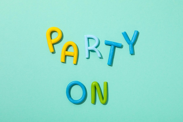 The word party is made of colored plasticine on a turquoise background