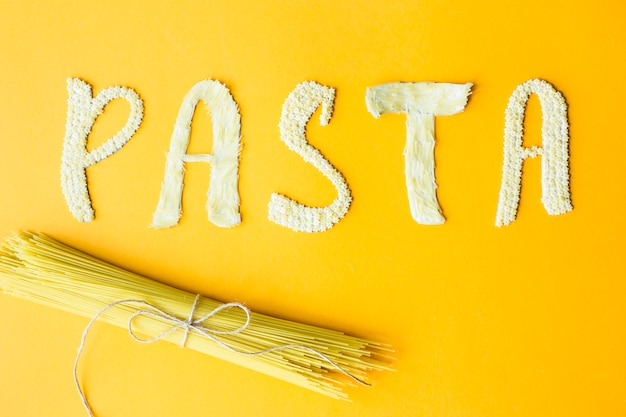 The word pasta is laid out in bulk letters from small raw macaroni