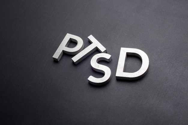 The word PTSD laid with silver metal letters on flat black background