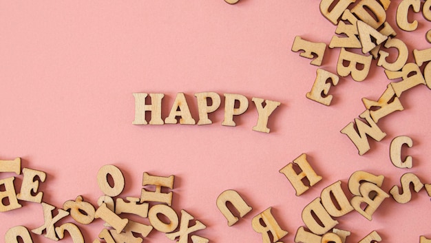 Word quotHappyquot written in English with wooden letters on a pink background