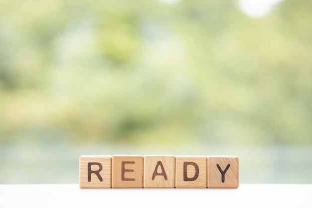 The word Ready on wooden cubes They lie on other cubes against the backdrop of the summer garden