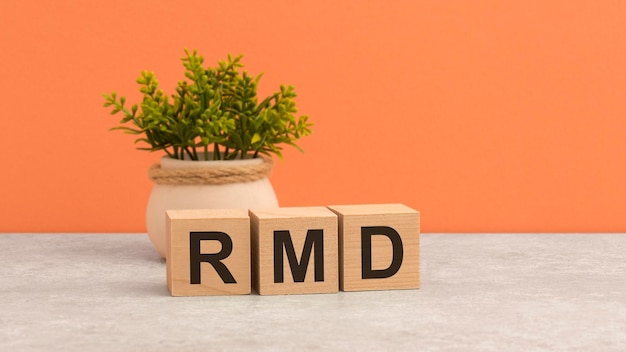 Word RMD on wooden cubes green flower on beautiful orange background business concept copy space