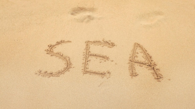 Word SEA written on wet beach sand.