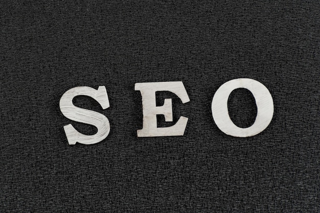 Word SEO from white wooden letters on black background. search engine optimization .