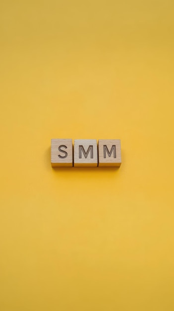 Photo the word smm made of wooden blocks on a yellow background representing simple social media marketing concepts digital marketing fundamentals marketing strategy smm basics