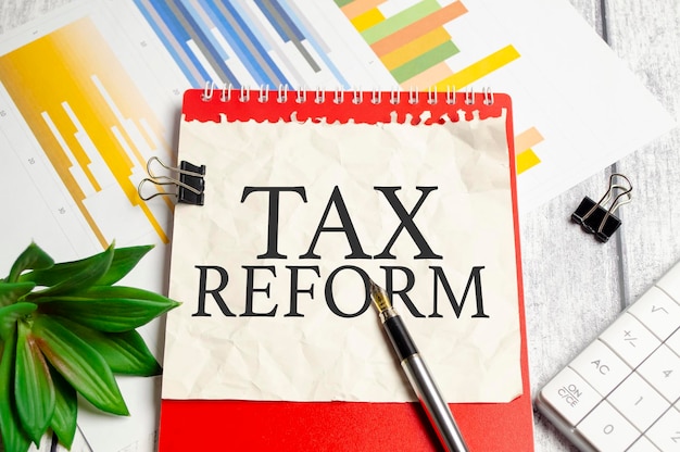 WORD tax reform on paper and red notebook on wooden background