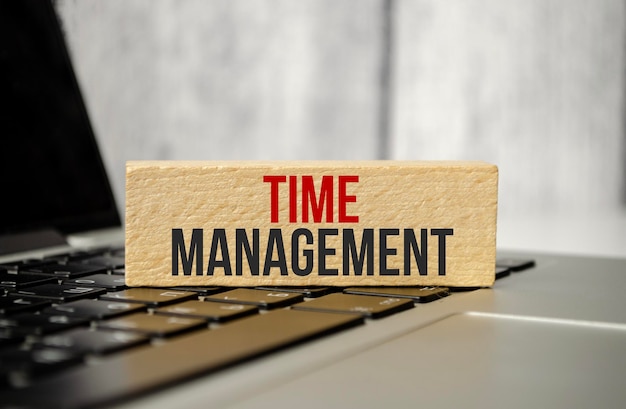 Word time management on wooden block with laptop on wooden background