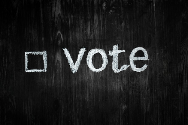 the word vote and an filled-in tick box  on a blackboard