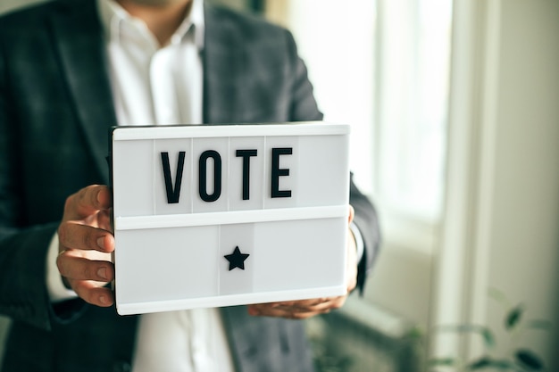 The word VOTE written on lightbox in men's hands. Election concept.