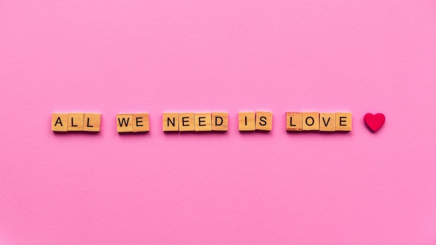 Words "All we need is love" on a pink paper