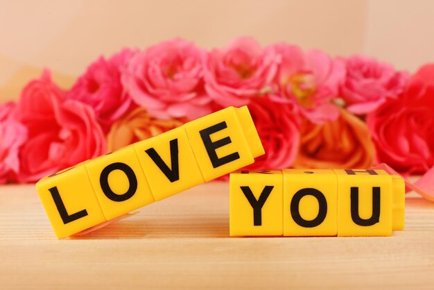 Words Love You formed from cubes with flowers on bright background