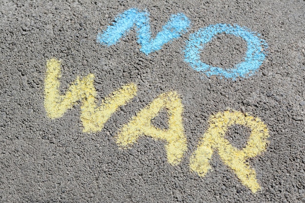 Words No War written with blue and yellow chalks on asphalt outdoors