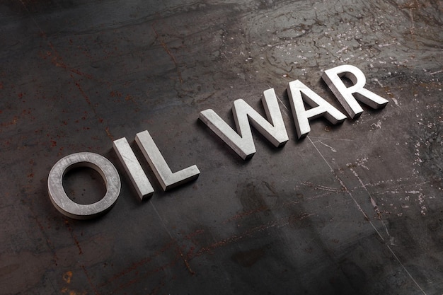 Words oil war laid in line with silver metal letters on rusted heavy hot rolled uncoated steel sheet surface in diagonal perspective