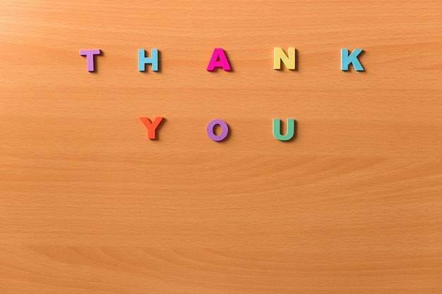 The words thank you in colored letters on a wooden background