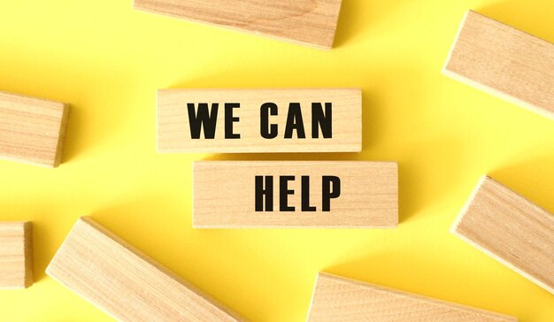 The words WE CAN HELP is written on a wooden blocks on a yellow background