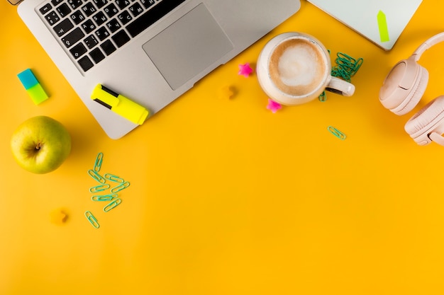 Work desk top view laptop and stationery on yellow background home schooling concept