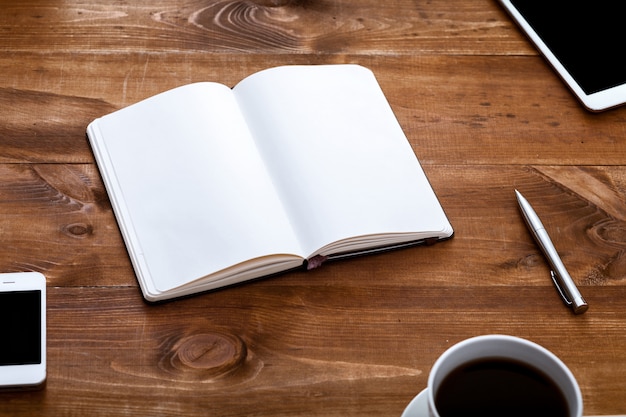 Work desk with open blank notebook for notes on brown wooden table