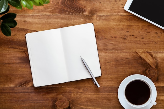 Work desk with open blank notebook for notes on brown wooden table