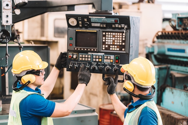 Work at factory.Asian worker man  working in safety work wear with yellow helmet and ear muff using equipment.in factory workshop industry machine professional