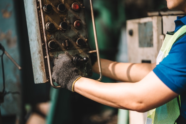 Work at factory.Close up hand of Asian worker man  working in safety work wear with yellow helmet and ear muff using equipment.in factory workshop industry machine professional