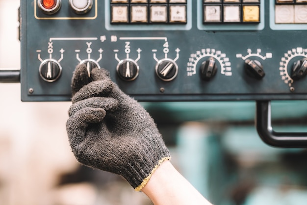 Work at factory.Close up hand of worker man working in safety work wear with yellow helmet and glove using control panel.in factory workshop industry machine professional