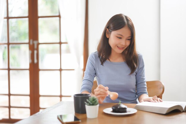 Work from home concept Business women is reading book and eating dessert to relax in living room