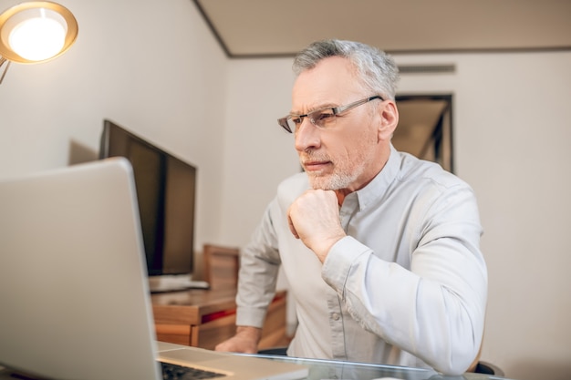 Work from home. Gray-haired man working from home and looking busy