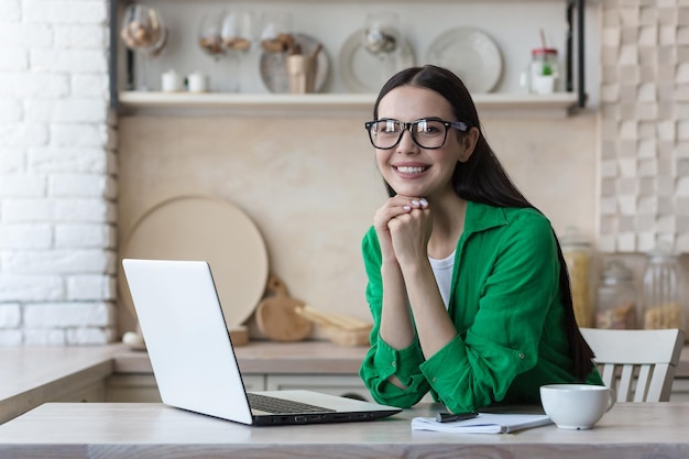 Work at home online portrait of young beautiful woman in glasses and green clothes freelancer