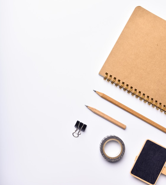 Work space with notebook, pencil and black board over white background