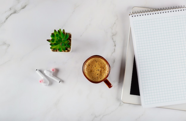 Work space with notebook with wireless headphone and coffee on a digital tablet, office desk