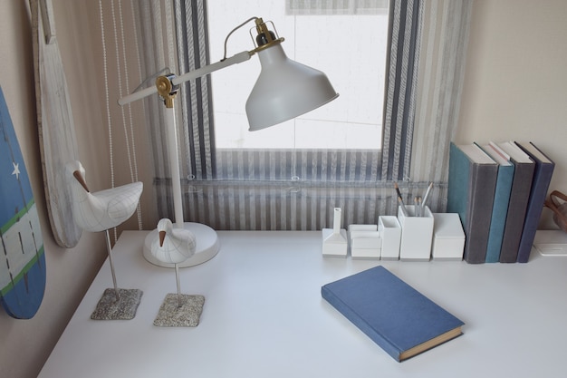 Work table with lamp,pencils and books in working room