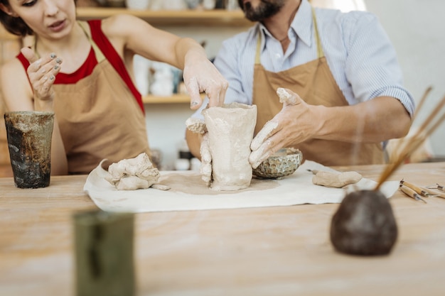 Photo work with husband. appealing dark-haired female ceramist working together with her handsome husband