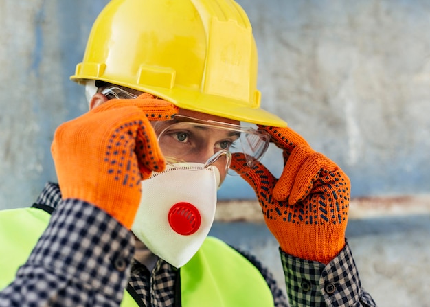 Worker adjusting his protective glasses while wearing mask and gloves