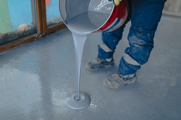 Photo the worker applies gray epoxy resin to the new floor