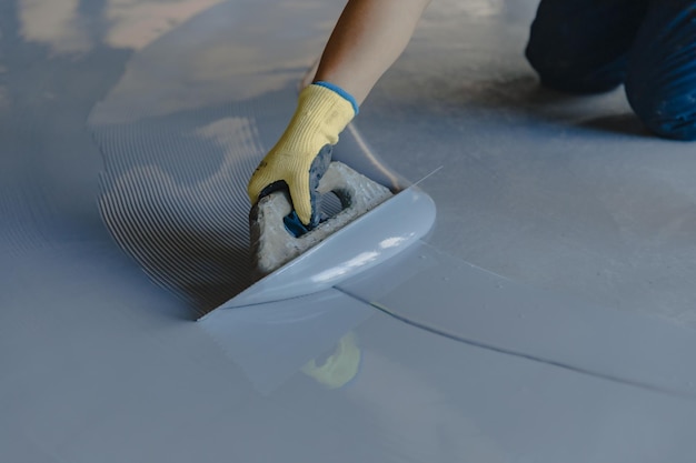 Photo the worker applies gray epoxy resin to the new floor