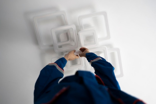 A worker in blue uniform fixing the led light at home