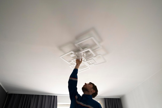 A worker in blue uniform fixing the led light at home