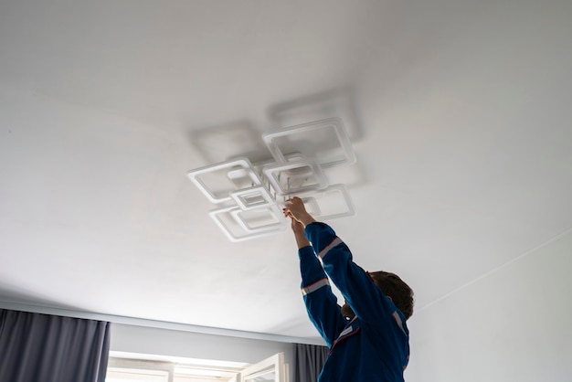 A worker in blue uniform fixing the led light at home