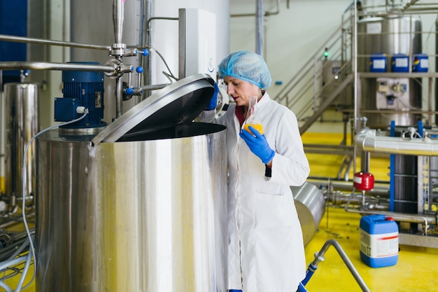 Worker at bottling factory checking juice quality.