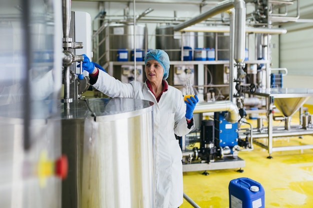 Worker at bottling factory checking juice quality.